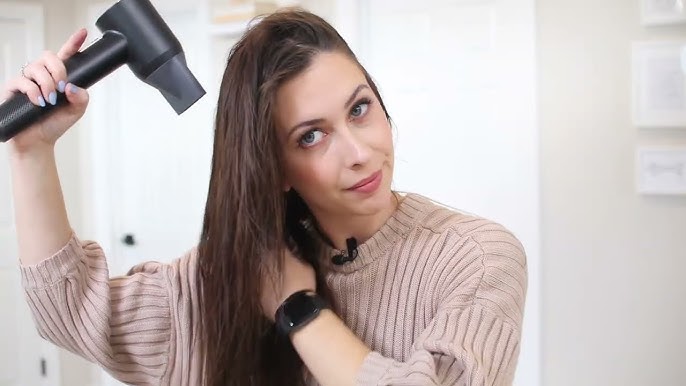 a woman use hair dryer with concentrator nozzle to dry her hair